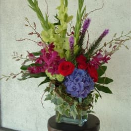 Tall mixed floral arrangement in a square glass vase