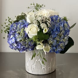 Blue hydrangeas and white roses arranged in a textured vase