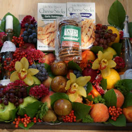 Fruit and snack gift tray with wine bottles and yellow orchids