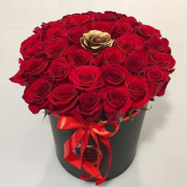 Red roses arranged in a black hatbox with a red ribbon