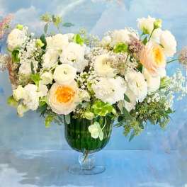 White and peach flowers arranged in a green glass vase