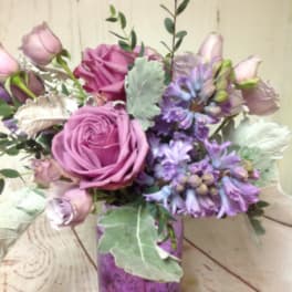 Lavender and pink roses with purple hyacinths in a purple glass vase