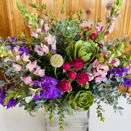 Mixed bouquet with pink roses, purple blooms, and green succulents in a wooden box