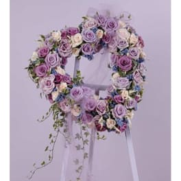 Heart-shaped floral wreath of lavender and pink roses on a stand