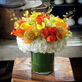 Bouquet of orange and yellow flowers in a green glass vase