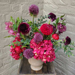 Mixed pink and purple flowers arranged in a beige vase