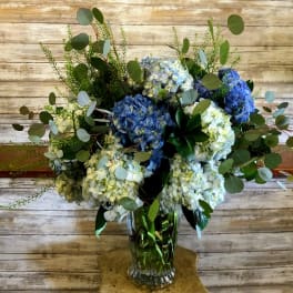 Blue and white hydrangea arrangement in a clear glass vase