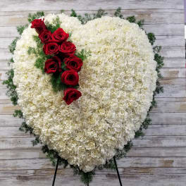 Heart-shaped white floral spray with red roses on a stand