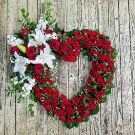 Heart-shaped floral wreath with red carnations, white lilies, and red roses