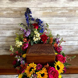 Colorful floral arrangement around a wooden urn on a rustic background