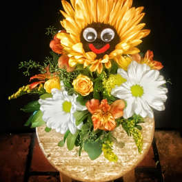 Sunflower-shaped floral arrangement with daisies and orange blooms in a round container