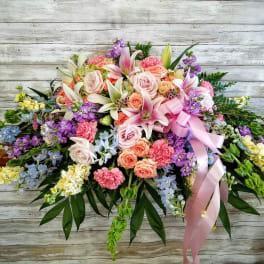 Large pastel floral spray with lilies, roses, and ribbon
