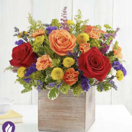Mixed bouquet of roses, carnations, and button mums in a wooden box