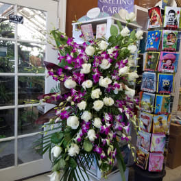 Tall arrangement of white roses and purple orchids on a stand