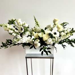 White floral arrangement in a rectangular vase with long greenery