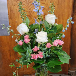 Pink and white roses with blue delphinium in a glass vase