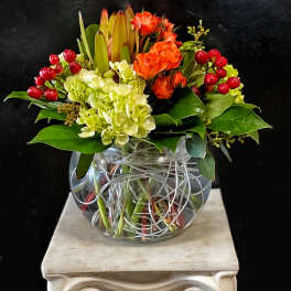 Orange roses and pale hydrangeas in a clear glass vase