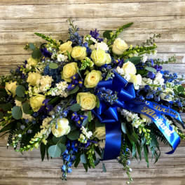 Blue and yellow floral spray with ribbon on a wooden background
