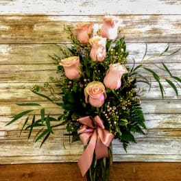 Pink roses arranged in a glass vase with a satin ribbon