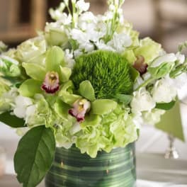Green and white floral arrangement in a glass vase