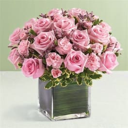 Pink roses and carnations arranged in a square glass vase