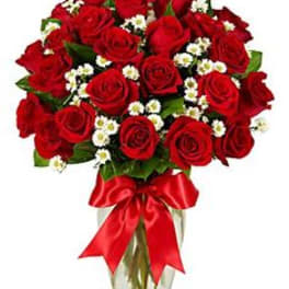Bouquet of red roses with small white filler flowers in a glass vase