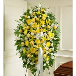 Yellow and white funeral spray on a stand with a white ribbon