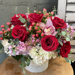 Red roses and pink flowers arranged in a white vase