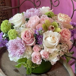 Pastel bouquet of roses, chrysanthemums, and orchids in a green vase