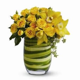 Yellow roses and orchids in a striped glass vase