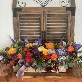 Colorful mixed flower arrangement in a rustic wooden box with a ribbon