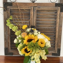 Sunflower and white rose arrangement in a striped tin container with a yellow ribbon