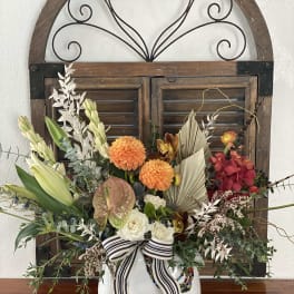 Colorful floral arrangement in a white vase with a striped ribbon