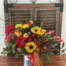 Mixed bouquet of red, yellow, and orange flowers in a metal vase