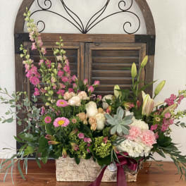 Mixed floral arrangement in a rustic rectangular container with pink and white blooms