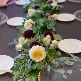 Long floral table runner with cream and burgundy roses on a dining table