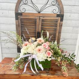 Pastel flower arrangement in a glass vase with a ribbon bow