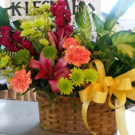 Mixed flower arrangement in a woven basket with a yellow ribbon
