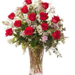 Red roses in a clear glass vase with small filler flowers