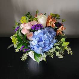 Mixed bouquet with blue hydrangea, pink roses, and white rose in a white vase