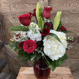 Red roses and white hydrangeas in a red glass vase