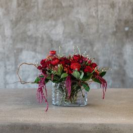 Red rose arrangement in a clear glass vase with trailing pink accents