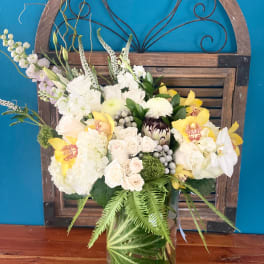 Mixed white and yellow floral arrangement in a glass vase