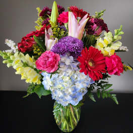 Mixed bouquet in a glass vase with pink, purple, red, and yellow flowers
