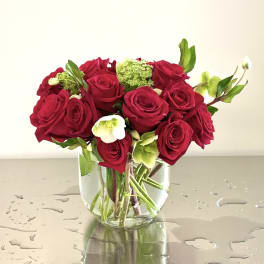 Red roses arranged in a clear glass vase with white flowers
