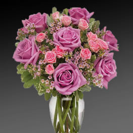 Pink and lavender roses arranged in a clear glass vase