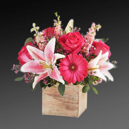 Pink roses and lilies arranged in a wooden box