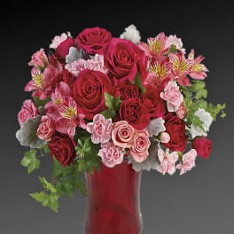 Pink and red rose bouquet in a red glass vase