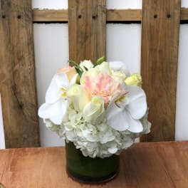 White and blush floral arrangement in a green glass vase