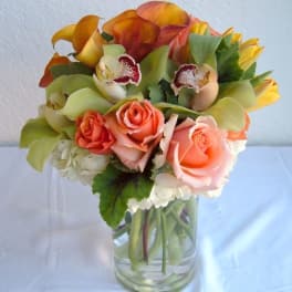 Bouquet of orange roses and calla lilies in a clear glass vase